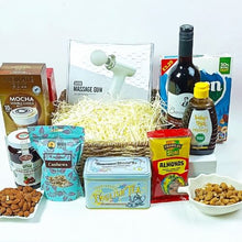 Gourmet gift basket with snacks, tea, and a bottle of wine on a white background