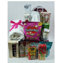 Gift basket with various items including a towel, snacks, and drinks on a white background