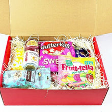 Open box containing various snacks and drinks including Butterkist, Swee, and Fruit-tella products.
