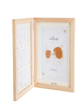 A wooden photo frame with a double standing design, featuring a large aperture for a baby's first birthday and twelve smaller apertures for month by month growth, with a white matte border and a beige background.