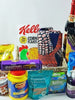 A gift basket containing various food items including cereal, dates, and snacks, with a decorative scarf added on top.