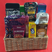 Treats, tea towel, gift items and snacks arranged nicely in a handcrafted basket against a red background