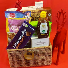 Gift basket with Dairy Milk chocolate, honey, and other items on a red background