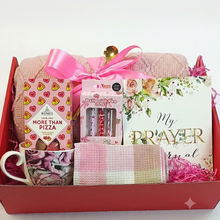  Pink & red themed gift box set containing a pink floral mug, a pink and white checkered towel, a pink knitted blanket tied with a pink ribbon, a box of Bonds More Than Pizza sweets, a pack of 3 Pens, and a floral prayer journal that reads 'My prayer journal, 21 days of prayers, praise & devotion 