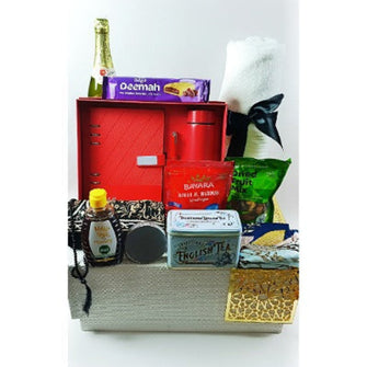 A luxurious leather box gift set with various items including Arabic written notepad, pen, temperature reading bottle, bath towel, tea, nuts, dried fruits, apple cider, date bar, honey, prayer mat, tasbih, mints, and an XL headscarf.