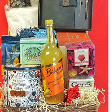 Gift basket with various items including a bottle of Belvoir Spiced Ginger Punch , treats, & festive celebration essentials on a red background