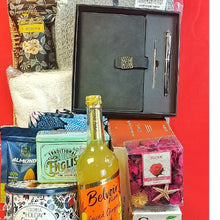 Gift basket with a notebook, pen, and various items on a red background