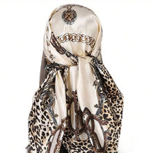 Mannequin display of ornate silk scarf with acream background, gold chain with leopard skin design in brown  