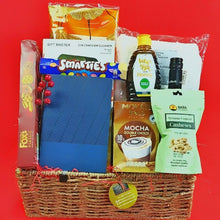 Golden cheer Gift basket showinh snacks, drinks, and a blue book on a red background