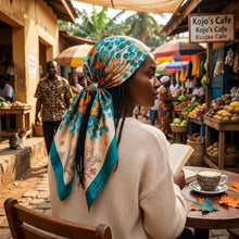 Model wearing the Azure Leaves silk scarf tied as a headscarf, showcasing the teal and orange leaf print on a smooth satin fabric.