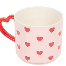 Pink mug with red heart patterns and a red handle on a white background