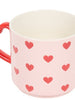 Pink mug with red heart patterns and a red handle on a white background