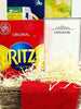 A gift basket arrangement featuring a red Ritz crackers box, a blue and green tea box with a portable juicer, a white Longfine diffuser box, shredded paper filler, and a folded red tea towel in a woven basket.
