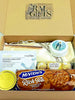 A curated gift box from Ral Gifts containing a McVitie's Rich Tea biscuit, a tin candle, a Sadoer eye mask, a praying rosary in a round case, a pen, scarf , notepad and Ferrero Rocher chocolates, all arranged inside a brown cardboard box.