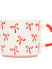 White mug with red heart handle and red bow pattern on a white background