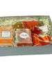 Gift box with a variety of items including a scarf, tea, perfume and cookies on a white background