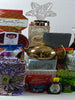 A collection of various food items and gifts arranged in a gift basket, including a golden teapot, books, and other assorted items.