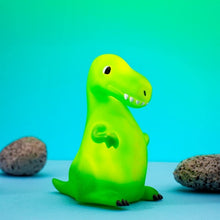 Green dinosaur night light on a blue background with rocks