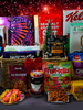 A festive hamper containing a variety of food items including cereal, nuts, biscuits, chocolate, granola, and fruit sweets, all packaged in colorful Christmas-themed packaging.