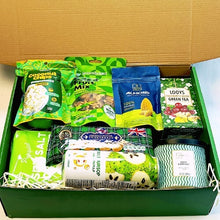 Assorted snacks, nuts and candle packed in a big green box 