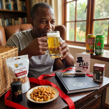 Father enjoying a beer with snacks and Father's Day-themed items on a table.