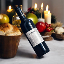 Bottle of La Merit wine with bread and fruit on a table with candles in the background