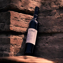 Wine bottle labeled 'La Merit' against a stone wall