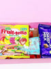 Open pink box containing Fruit-tella Duo Stix and Cadbury Dairy Milk chocolate bars on a white background.