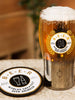 A beer glass with a gold finished base, featuring the text 'Greatest Beer Drinker', alongside a matching coaster with the same text.