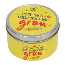 Yellow tin candle inscribed Thank you for helping me grow and pencil underneath. Against a white background 